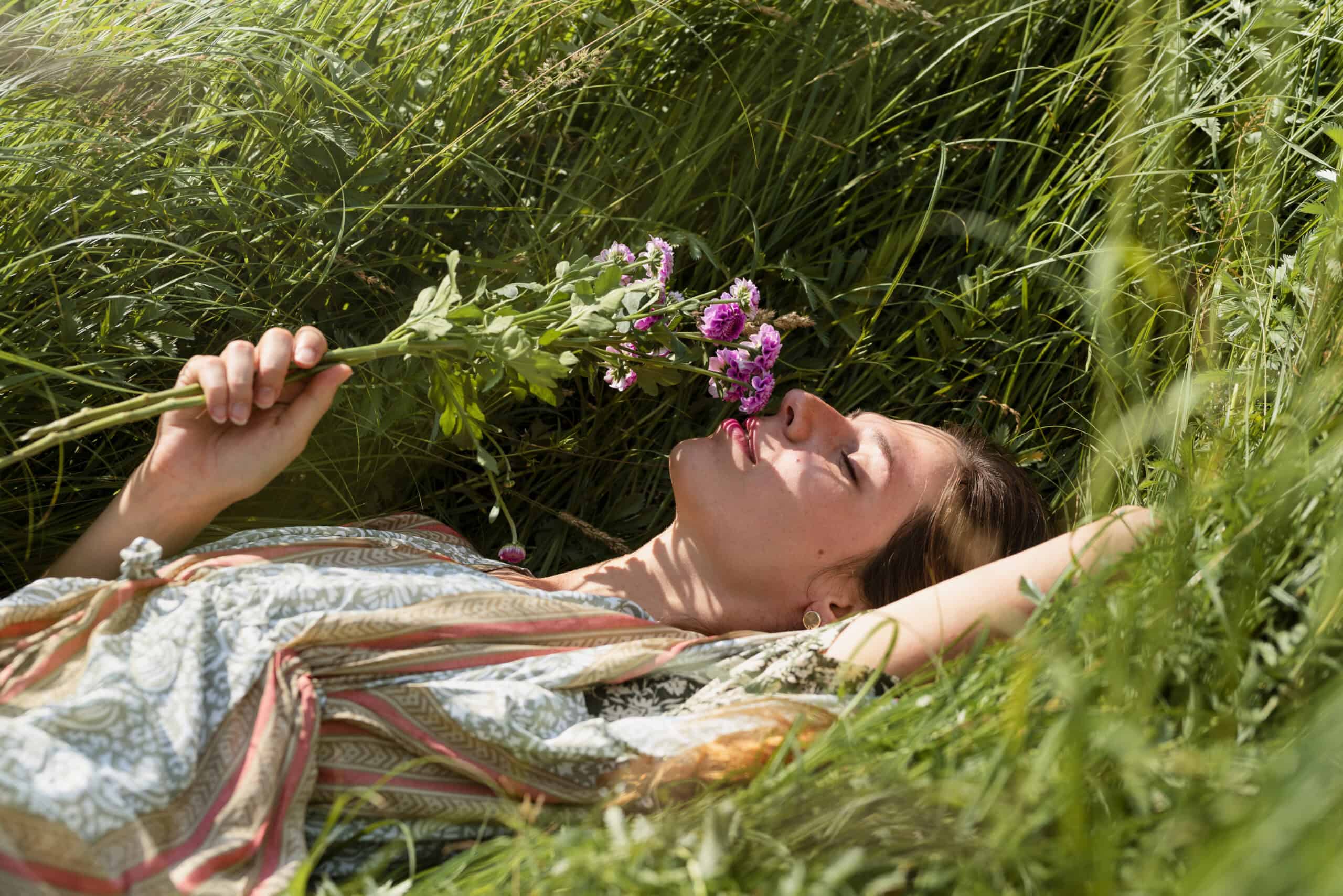 Personne allongée sereinement dans un champ de fleurs, illustrant le bien-être et la création de site pour sophrologue.